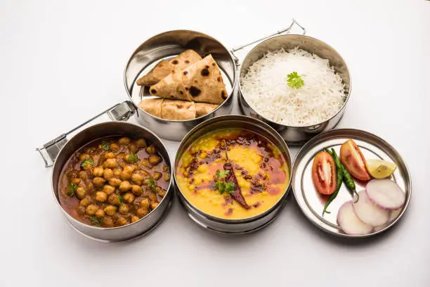Indian vegetarian Lunch Box or Tiffin made up of stainless steel for office or workplace, includes Dal Fry, Chole Masala, Rice with chapati and salad
