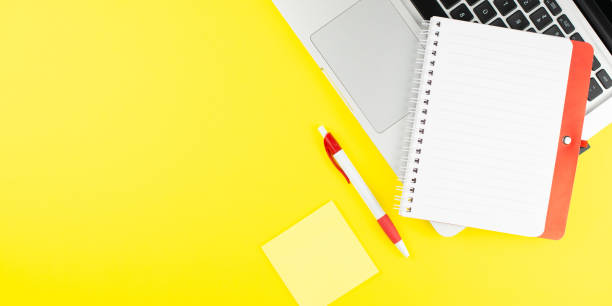 istock Red notepad, pen, colorful clips and laptop on yellow background. Flat lay with copy space. Workplace in the office. 1256245986