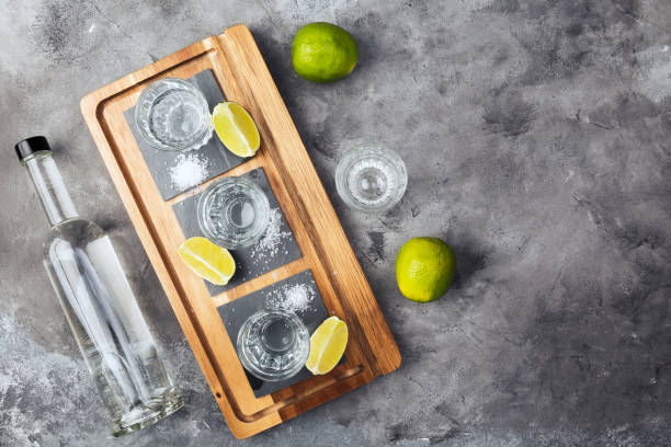 bottiglia e colpi di tequila, limes, sale su tavola di legno. visualizzazione superiore, spazio di copia - tequila shot tequila salt lemon foto e immagini stock