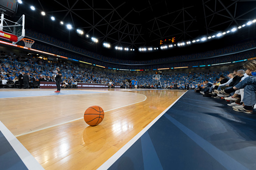 Basketball on court in stadium.