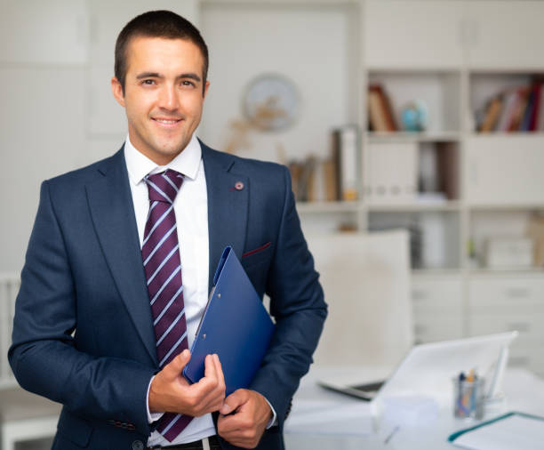 istock Smiling businessman with folder of documents in office 1256250597