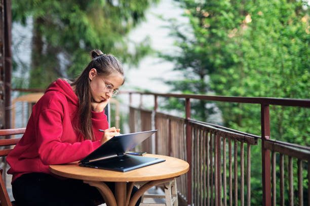 nastoletnia dziewczyna robi pracę domową na balkonie - wireless technology serious education enjoyment zdjęcia i obrazy z banku zdjęć