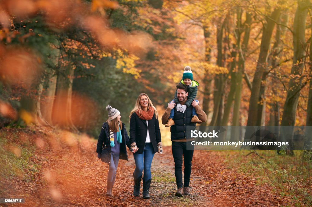 어깨에 아들을 안고 있는 아버지와 함께 가을 삼림 지대 길을 따라 걷는 가족 - 로열티 프리 가족 스톡 사진