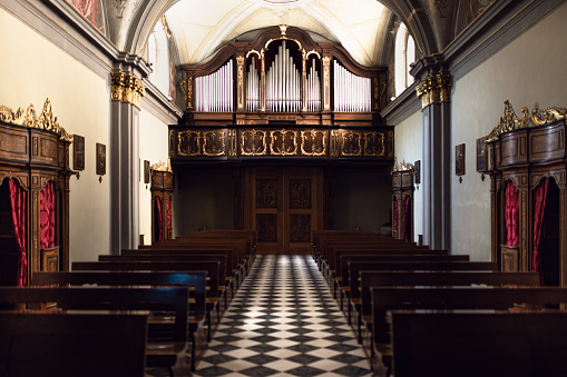 The interior of a neo-Byzantine church: view of the pipe organ, the confessionals and the wooden benches for prayer