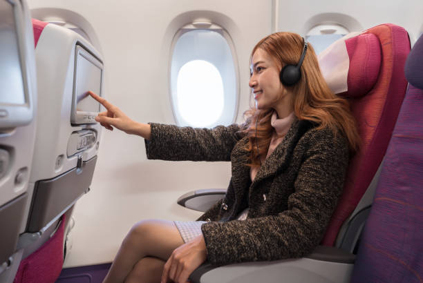 istock woman touching LCD entertainment screen on airplane in flight time. 1256261296