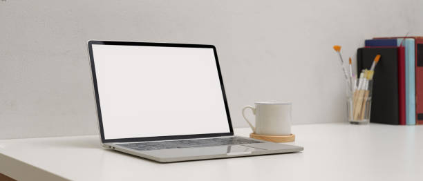 istock Simple workspace with mock up laptop, cup, copy space painting brushes and books on white table 1256262094