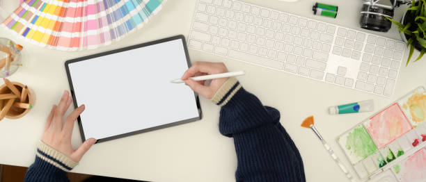 istock Female designer working on mock up tablet with stylus pen on white worktable with painting tools 1256262105