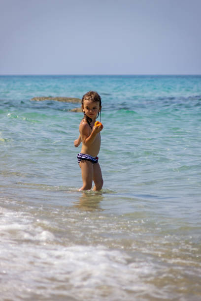 little girl eating a peach in the sea