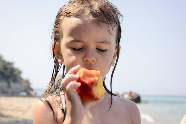istock little girl eating a peach 1256262356