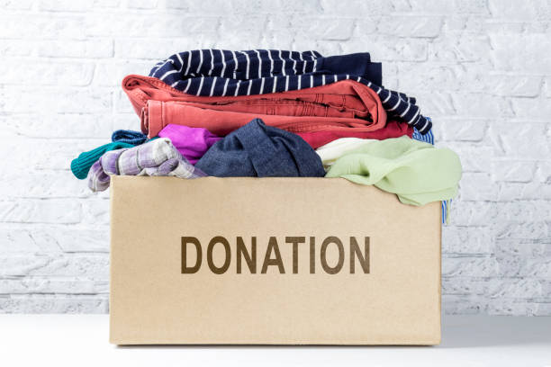 Box of clothing for donation against white wall Box of clothing for donation against white wall. Donation box in room. Concept donation. clothing donation stock pictures, royalty-free photos & images