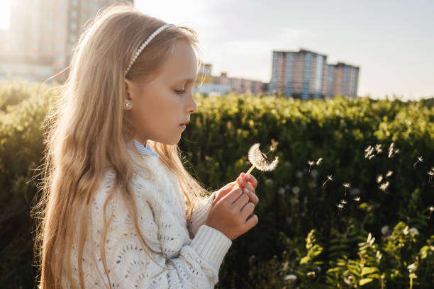 istock A girl blows on a dandelion in a field. 1256268214