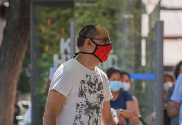 een mens die een gezichtsmasker van spiderman draagt - spider man stockfoto's en -beelden