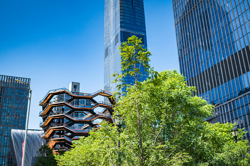 New York City, NY, USA - May 27, 2019: The Vessel, also known as the Hudson Yards Staircase designed by architect Thomas Heatherwick between skyscrapers.