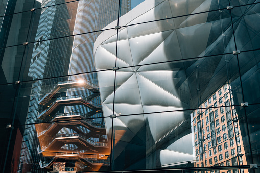 New York City, NY, USA - May 27, 2019: The Vessel, also known as the Hudson Yards Staircase designed by architect Thomas Heatherwick is on the left of the photo. The Shed, on the right,  is a cultural center in Hudson Yards, Manhattan, New York City. These attractions are on the High Line in New York City.