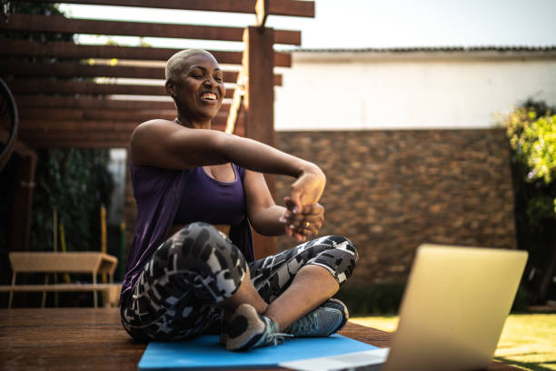 Woman doing a virtual exercise class, stretching her arms Woman doing a virtual exercise class, stretching her arms hand extended stock pictures, royalty-free photos & images