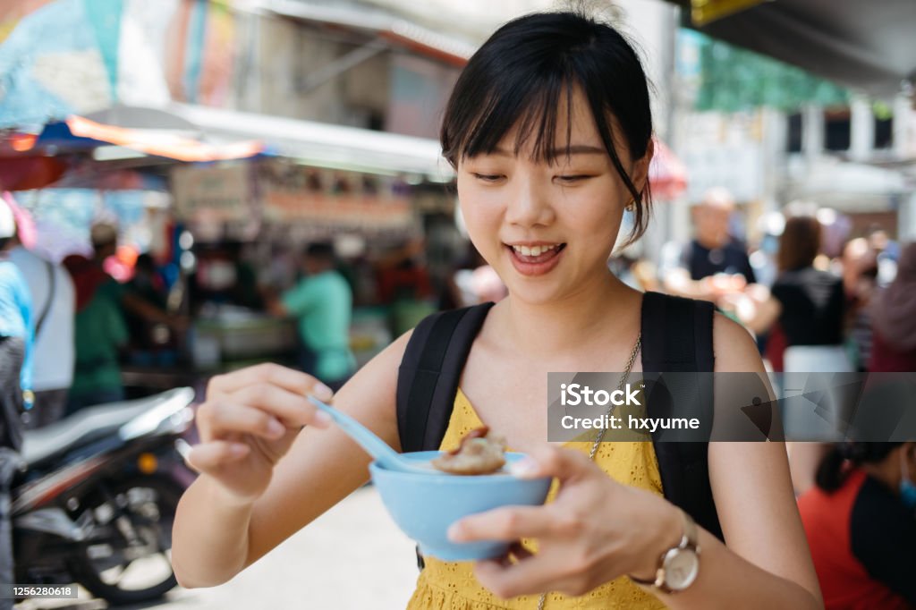 Young asian female tourist enjoying shaved ice dessert cendol at street Young asian female tourist is having cendol, a popular local shaved ice dessert in Malaysia. Malaysia Stock Photo