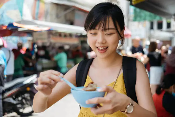 Young asian female tourist is having cendol, a popular local shaved ice dessert in Malaysia.