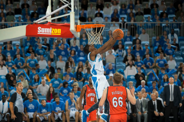 istock Basketball player slam dunking ball 1256281769