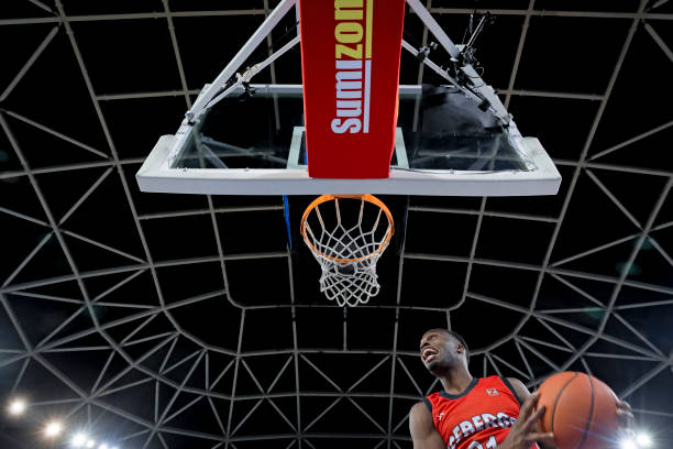 istock Basketball player slam dunking ball 1256281777