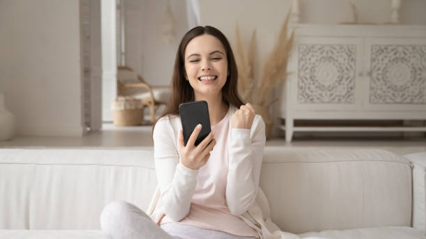 istock Overjoyed smiling woman looking at phone screen, celebrating success 1256286989