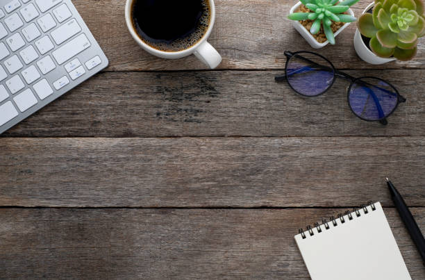 istock Top view from above of Blank open notebook, keyboard with glasses and coffee cup on wood table background. Workplace creative at home. Flat lay, Business-finance or education concept with copy space. 1256290455