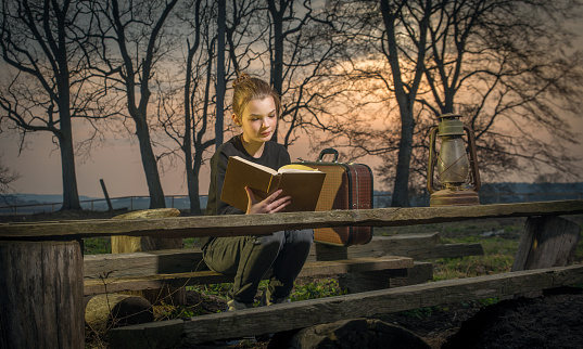 A girl reads a book at sunset.