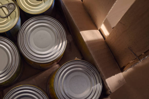 istock Tin cans in a cardboard box in morning morning rays. 1256292038