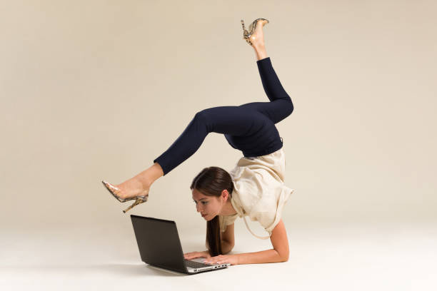 Young Gymnast Business Woman Stretching And Working On Computer Young Gymnast Business Woman Stretching And Working On Computer studio yoga adult action stock pictures, royalty-free photos & images