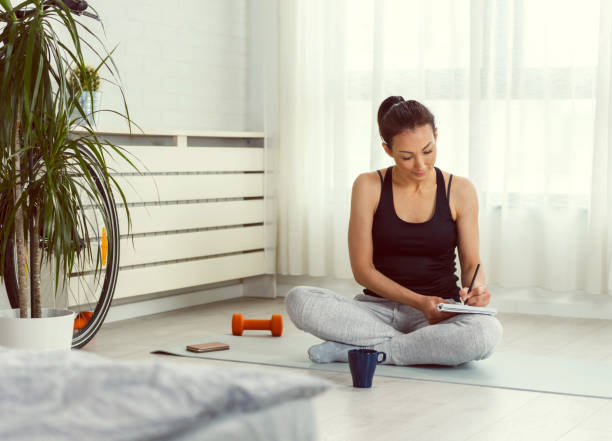 istock Young sporty woman writing into notebook after workout 1256293240