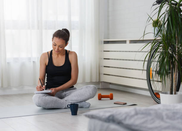 istock Young sporty woman writing into notebook after workout 1256293259