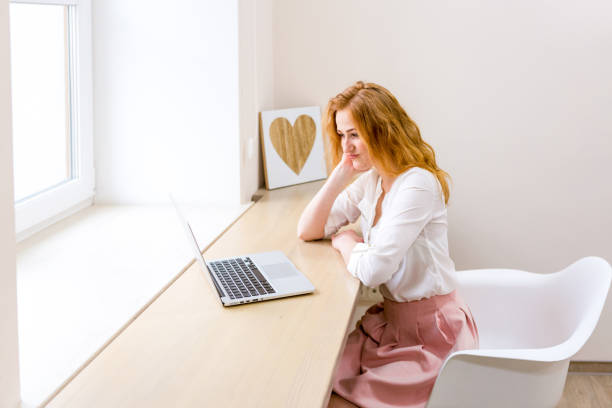 istock Beautiful young woman using laptop in office, typing, learning, watching webinars, video call, client consultations, distant work. Freelance and management. E commerce, education, Internet technology 1256293550