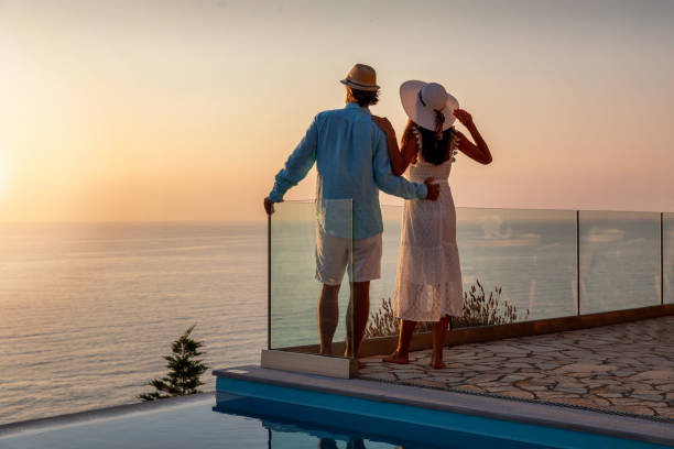 una pareja romántica en tiempo de vacaciones disfruta de la puesta de sol de verano junto a la piscina - honeymoon beach swimming pool couple fotografías e imágenes de stock