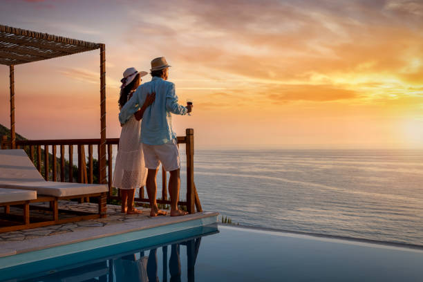 una pareja romántica en vacaciones de verano se alegra de la puesta de sol sobre el mar mediterráneo junto a la piscina - estilos de vida fotografías e imágenes de stock