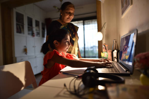 istock Girl completing homework using laptop with grandmother’s assistance 1256297327