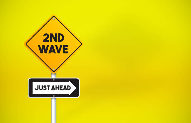 istock 2ND Wave Directional Road Sign On Yellow Background. Coronavirus Concept. 1256298159
