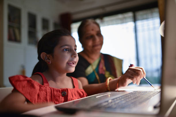 istock Girl completing homework using laptop with grandmother’s assistance 1256299030