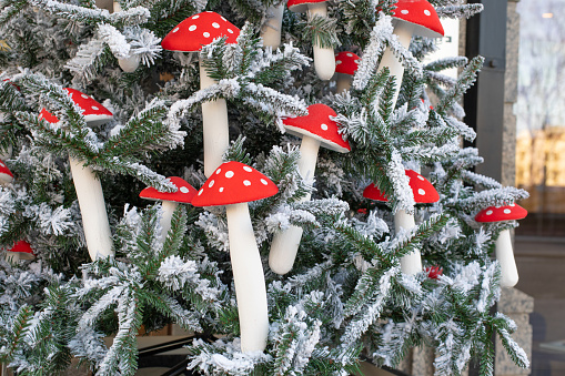 Artificial eco Christmas tree decorated with mushrooms with a red speckled hat with white snow. Decorations on the Christmas tree close-up amanita fly agaric, spruce in the snow