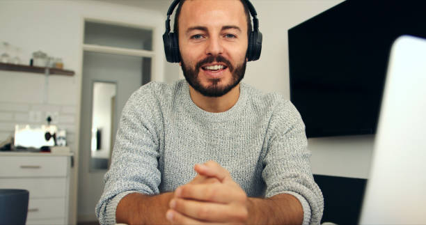 The busy but flexible life of a freelancer Portrait of a young man wearing headphones while using a laptop at home man video call pov stock pictures, royalty-free photos & images