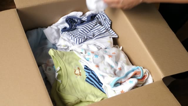 taking checking baby clothes packed in a cardboard box