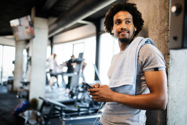 運動休憩でジムで携帯電話を使用して若い筋肉の男 - health club social gathering exercising sport ストックフォトと画像