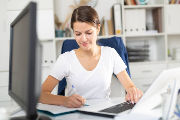 istock Smiling woman working with papers and laptop 1256302433