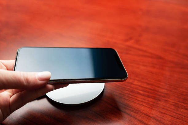 istock Hand holds a mobile smart phone for charging wirelessly by sharing battery via device. 1256302746