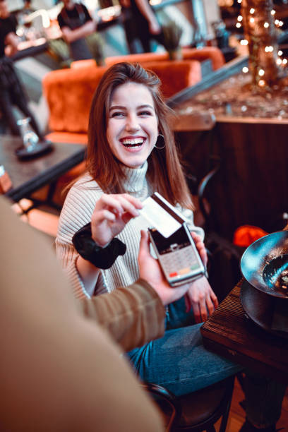 istock Smiling Female Paying For Coffee With Credit Card 1256305391