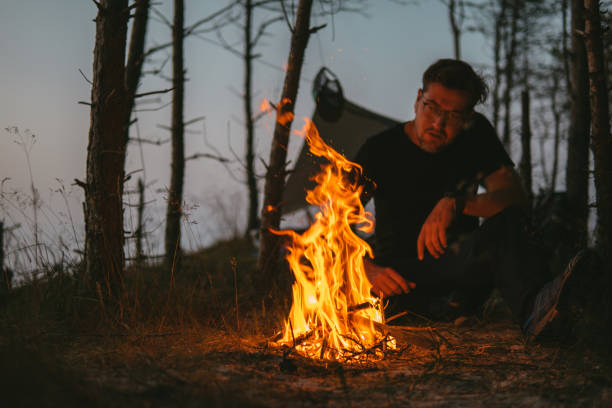 istock Man and bonfire on a beach camp 1256306338