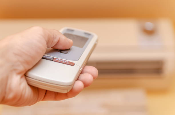 istock man's hand with a remote control is aimed at the air conditioner close up 1256306400
