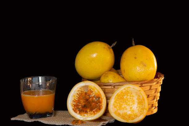 basket with ripe passion fruit, cut in half and a glass of refreshing juice. stock photo