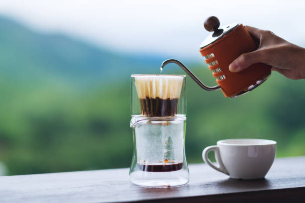istock a hand pouring hot water from kettle to make drip coffee with blurred nature background 1256309230