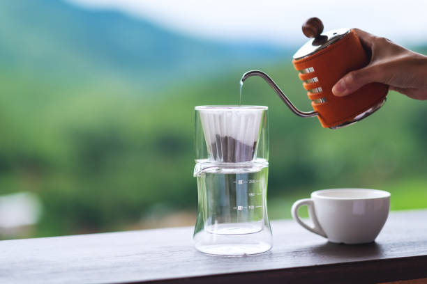 istock a hand pouring hot water from kettle to make drip coffee with blurred nature background 1256309247