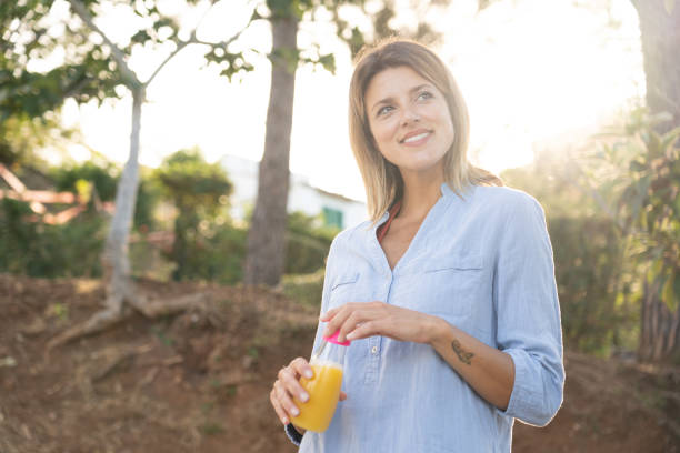 istock Beautiful girl drinking fresh orange juice 1256310147