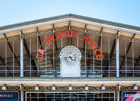 Paris, France - June 22, 2020: Close-up view of the sign and clock on the pediment of the Grande Halle de la Villette, a former slaughterhouse made of steel frame, converted into a cultural center.